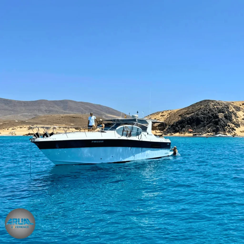 Primer plano nuestro barco ARUAL fondeado en aguas turquesas, con las icónicas Playas de Papagayo al fondo bajo un cielo despejado.