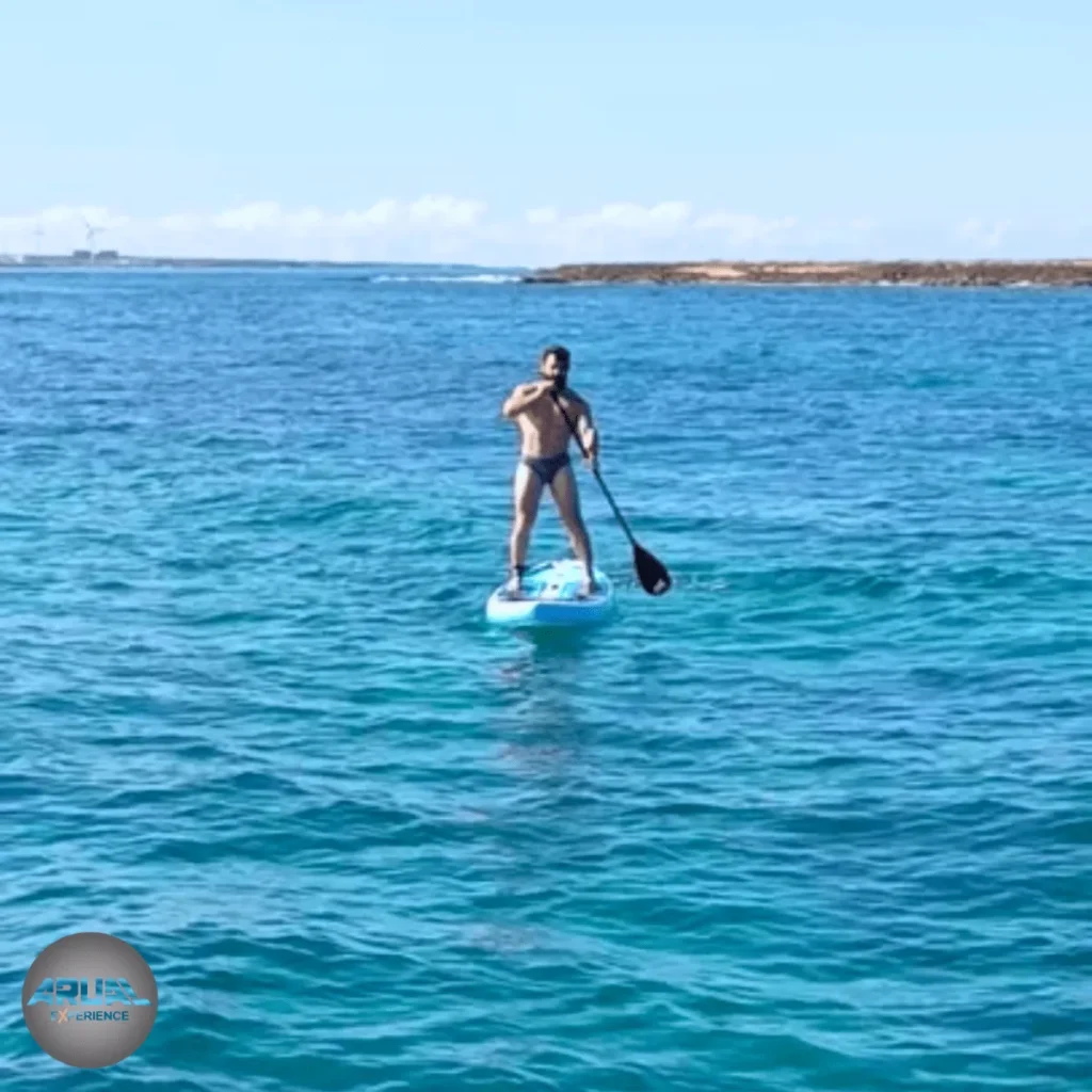 Cliente disfrutando del paddle surf sobre las aguas turquesas del Atlántico.