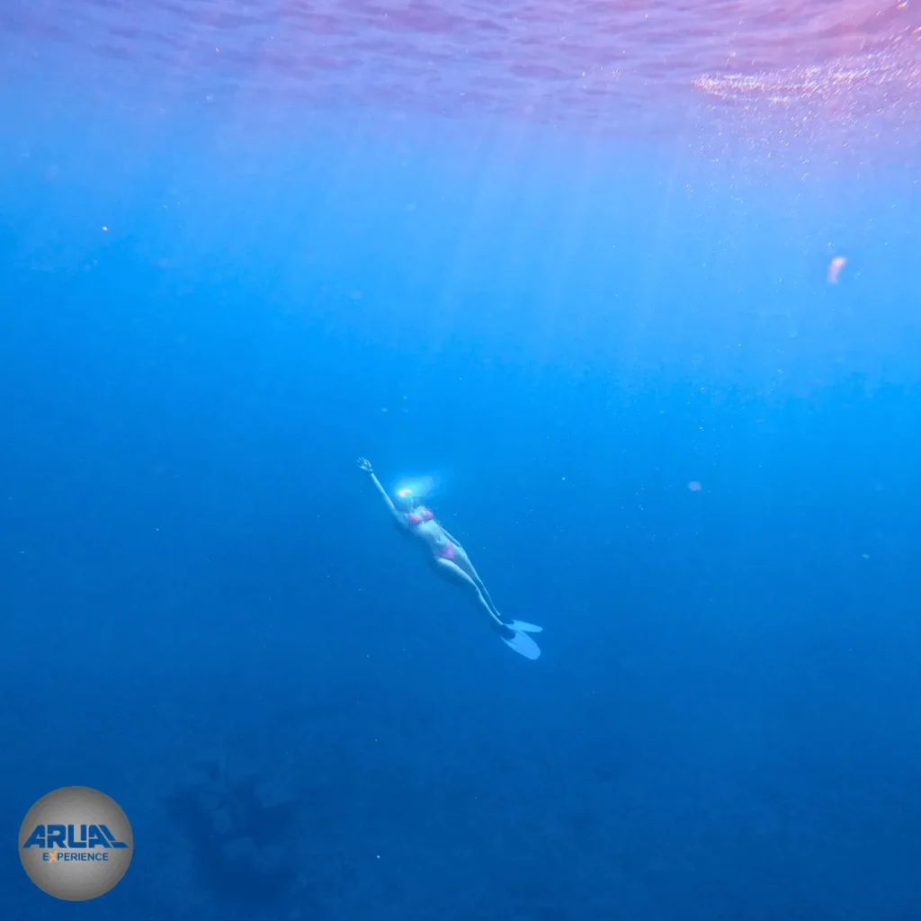 Toma submarina de una cliente disfrutando del snorkel en las aguas cristalinas de Canarias, mientras el sol refleja en su máscara.