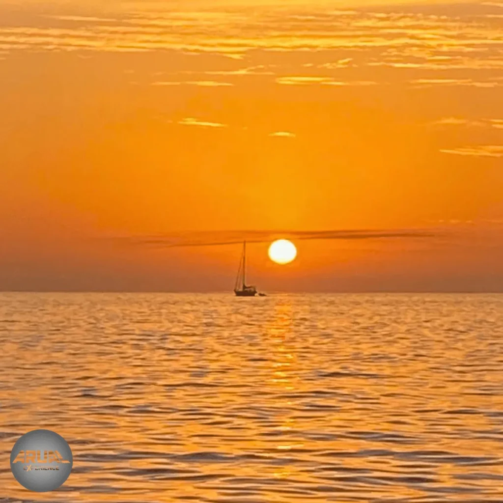Puesta de sol vista desde El Castillo de San Marcial del Rubicón, con el cielo teñido de tonos anaranjados y el mar tranquilo reflejando la luz.